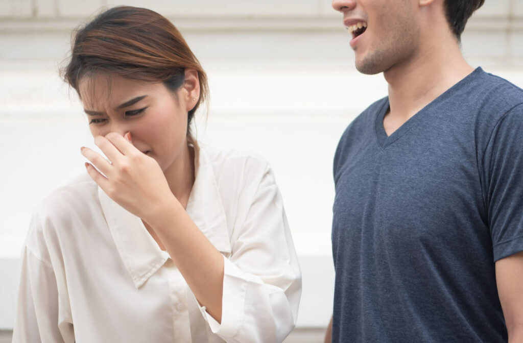 A woman suffering from a man's bad breath.