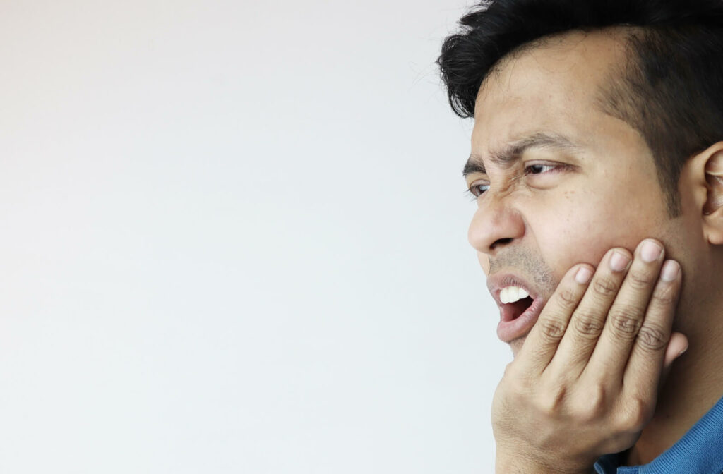 A close-up of a male holding his chin in pain due to an impacted wisdom tooth