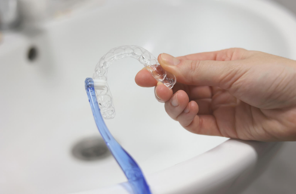 A person cleaning their Invisalign with a small brush.
