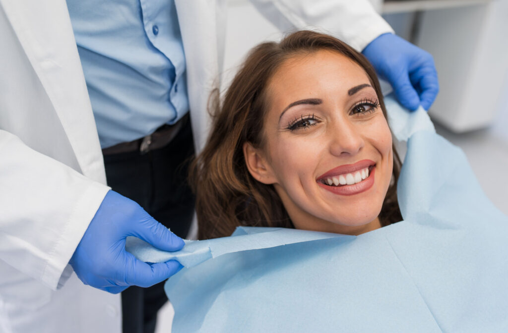 A Close-up of a woman smiling while her dentist applies a dental bib.