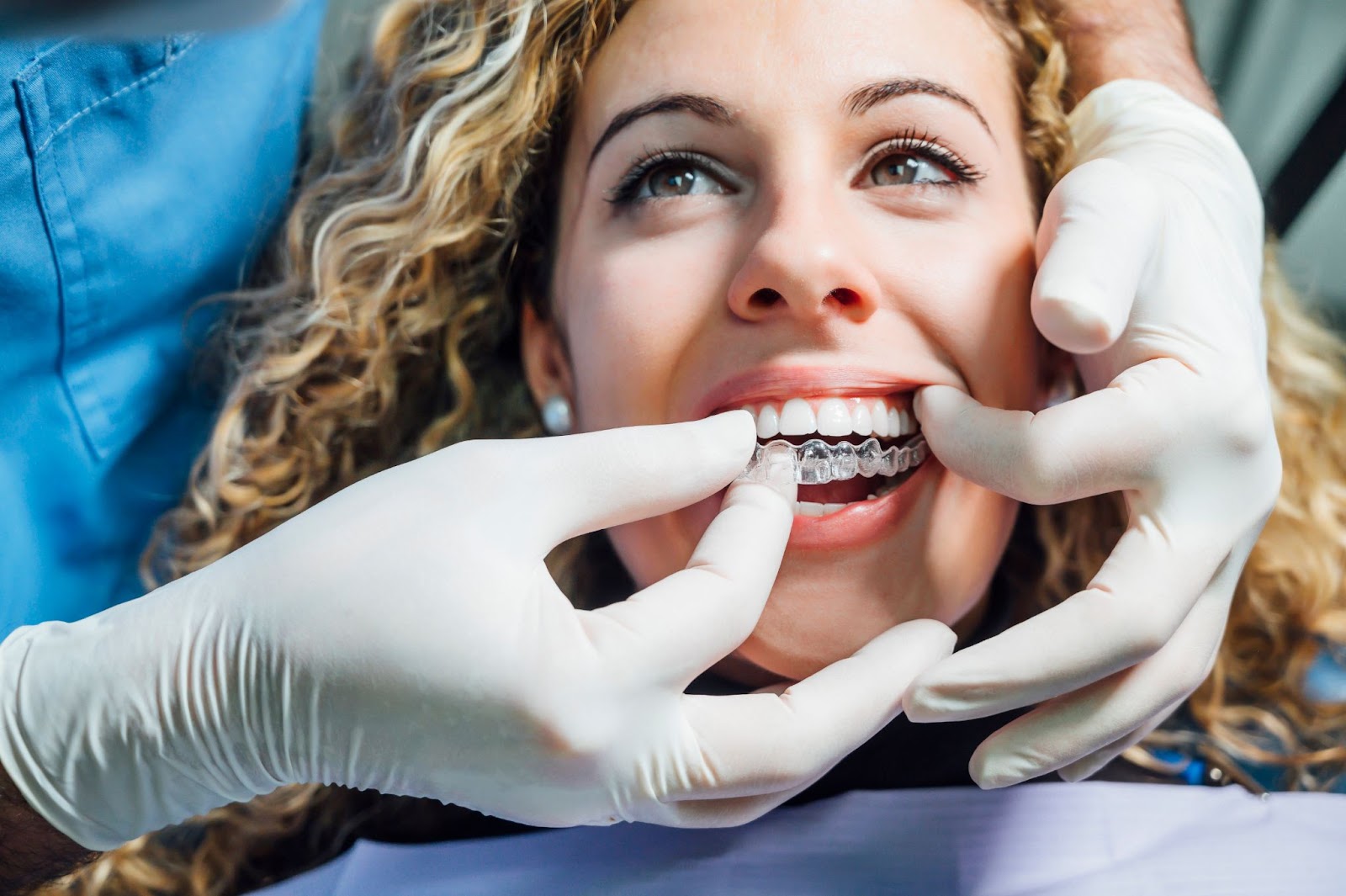 Dentist fitting Invisalign aligner on a smiling patient.