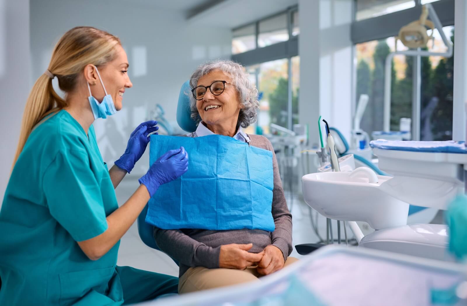 A dentist discusses the oral health of their older patient during an exam.