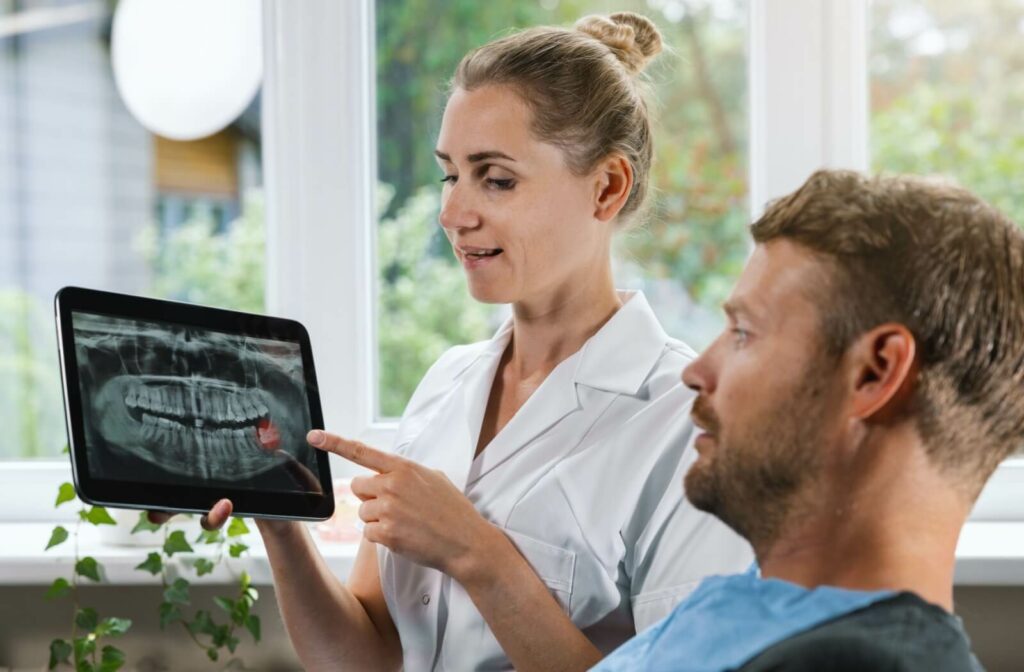 A dentist showing their patient an x-ray of their wisdom teeth growing in