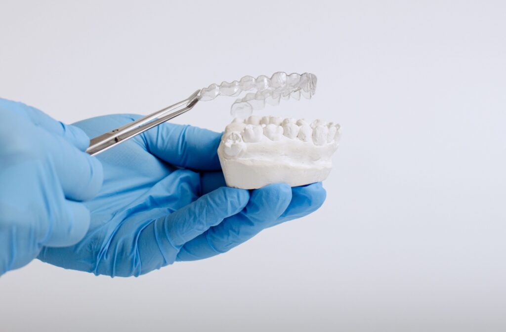 A pair of gloved hands holding a jaw cast and aligner.