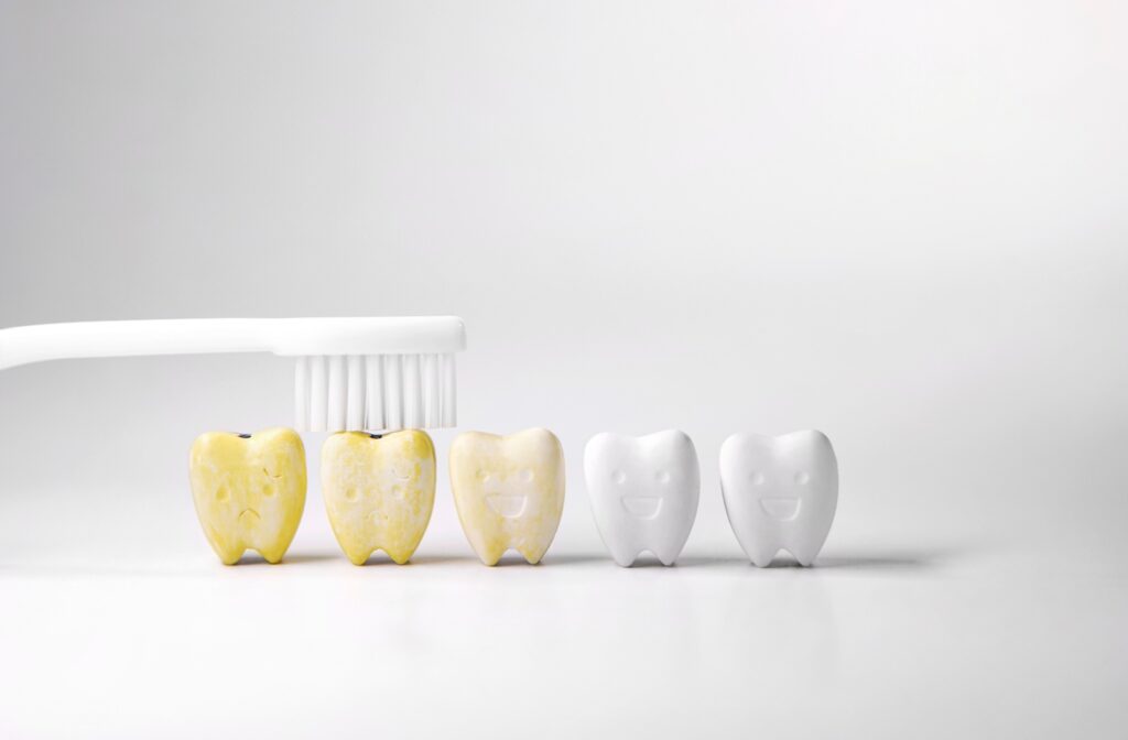 A toothbrush brushes across cartoon teeth changing from yellow to white.